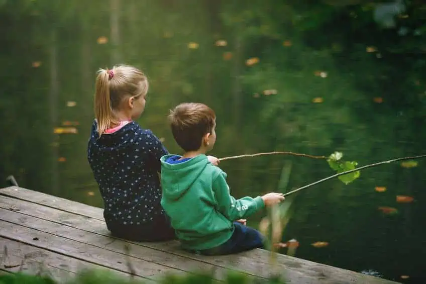 Small children sitting on a bench fishing on free dishing day.