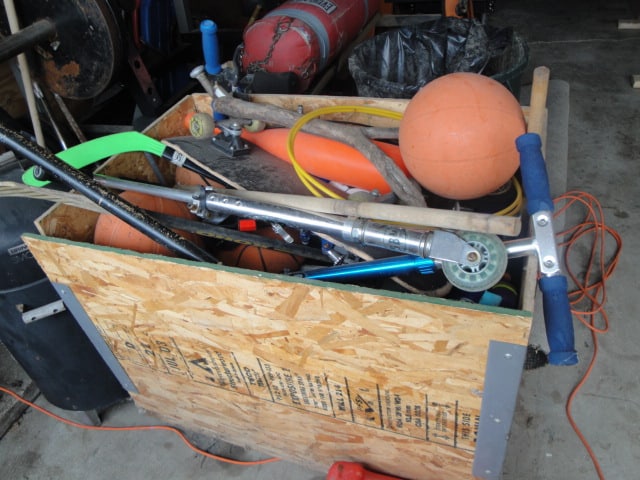 Box of scooters and sports equipment in garage.