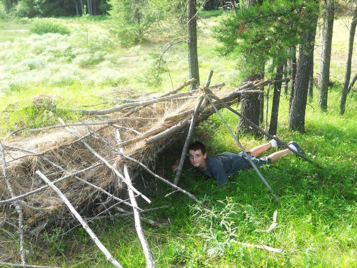 Young man build a makeshift fort from twigs and shrubbery.