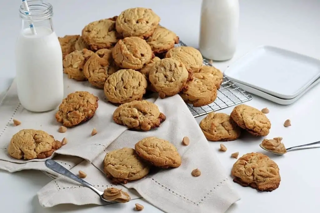 Peanut butter cookies surrounded by peanut butter chips and milk.