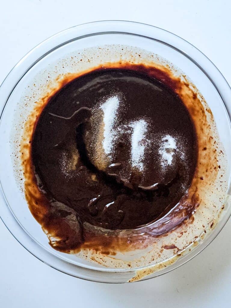 A glass bowl with mint chocolate chip ice cream cake and chocolate sauce in it.