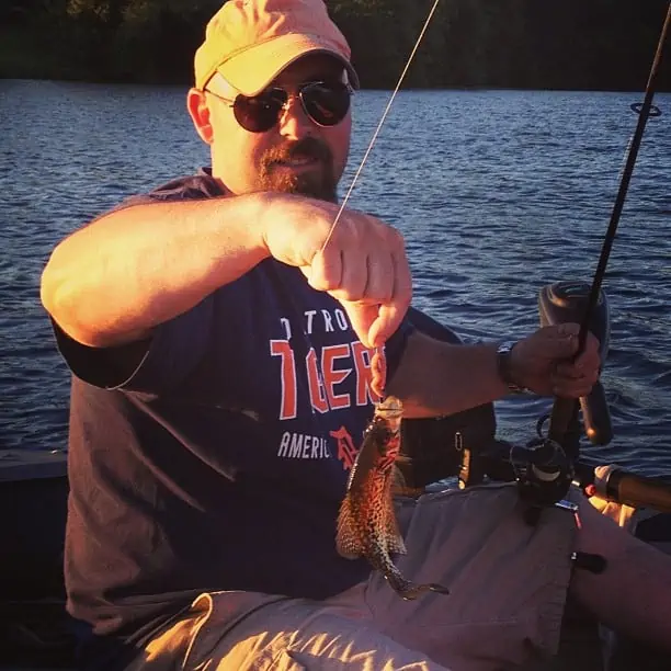 A man holding a fish on a boat in a body of water