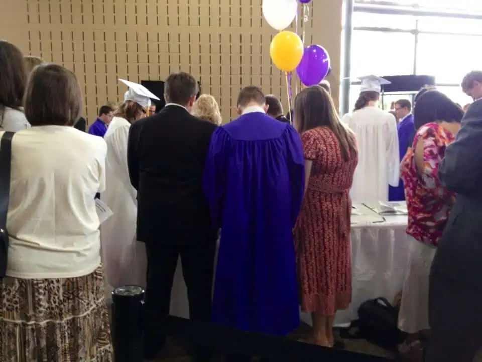 A group of people standing in front of a crowd of school graduates.