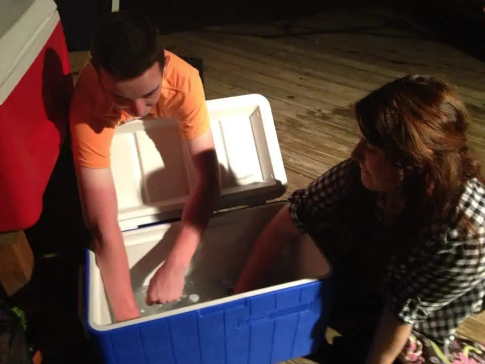 A group of people diving into a cooler and grabbing drinks.