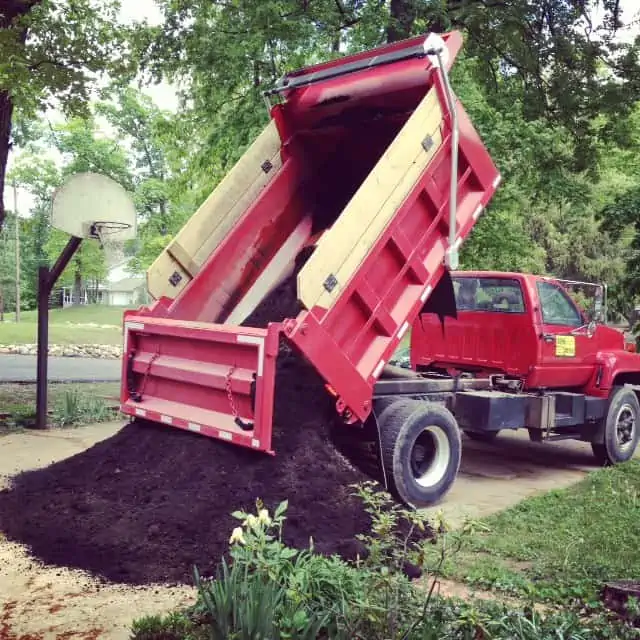 A truck is parked on the side of a dirt field