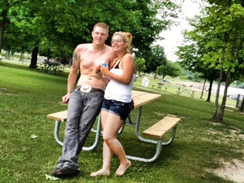 A couple leaning against a park bench.