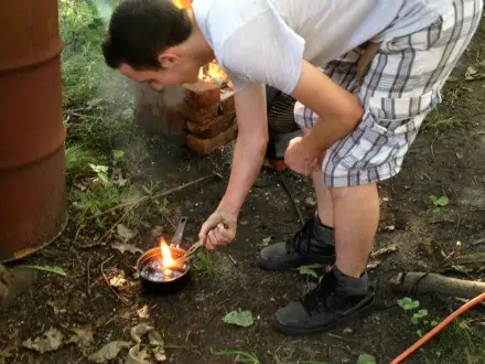 Young man burning an object in the woods.