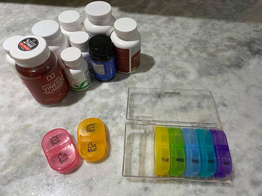 Several different pill bottles and pill dispensers to organize daily pill intake.