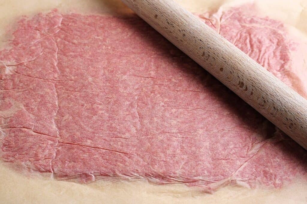 Place the ground hamburger in between two sheets of wax paper and use a rolling pin to flatten it out.