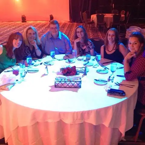 A group of people sitting at a table with a cake