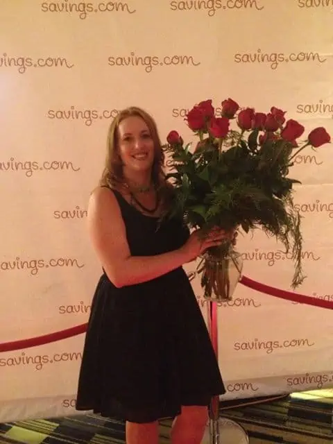 A woman posing for a picture with a bundle of flowers.