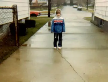 A small girl outside in the rain bundled in her coat.