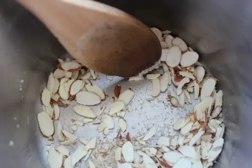 Diced almonds being cooked in a pan.