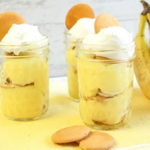 Banana pudding in a jar with whip cream and wafers.