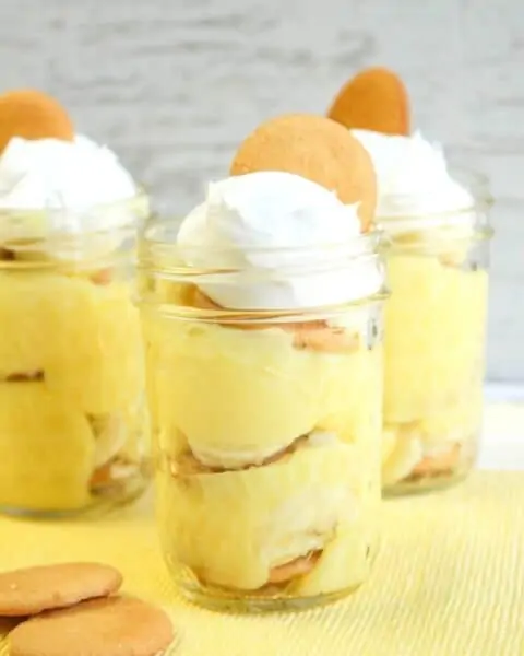 Banana pudding in a jar with whip cream and wafers.