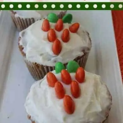 carrot cake cupcakes with orange and green M&Ms in the shape of carrots.