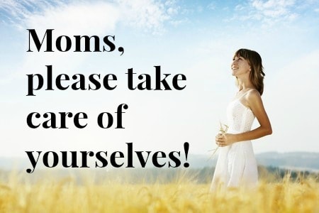 Woman standing in a field with sign that says \"Moms, please take care of yourselves.\"