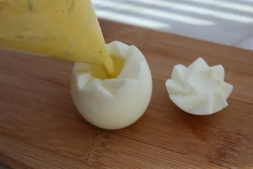 Deviled egg mixture being inserted back into the egg.