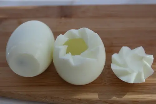 The top of a boiled egg cut out and the yolk removed.