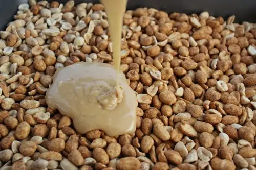PayDay sauce being poured over the oven roasted peanuts.