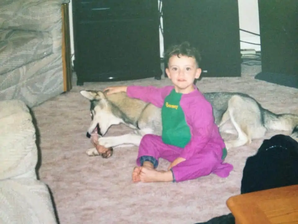 A small boy with a puppy dressed as Barney the dinosaur.