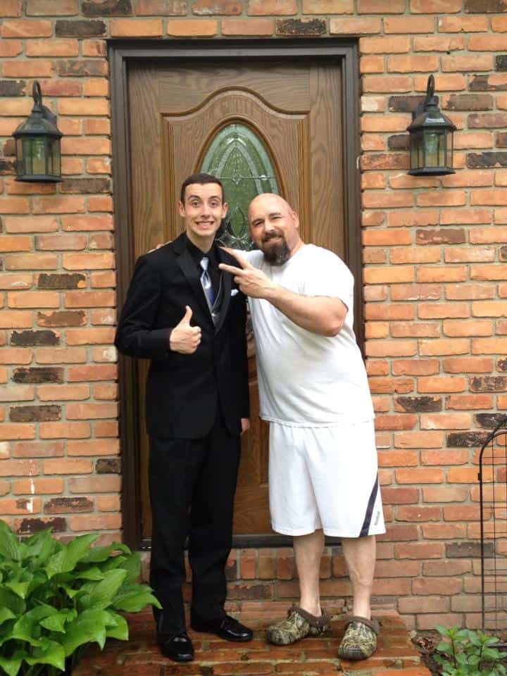 A father and son standing in front of their home door.