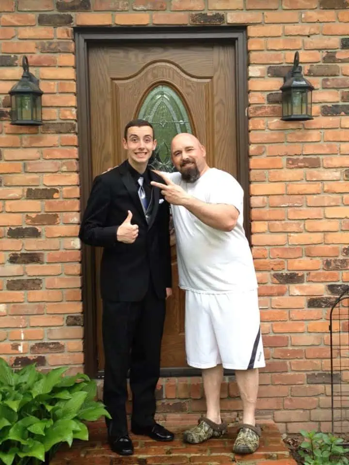 A father and son standing in front of their home door.