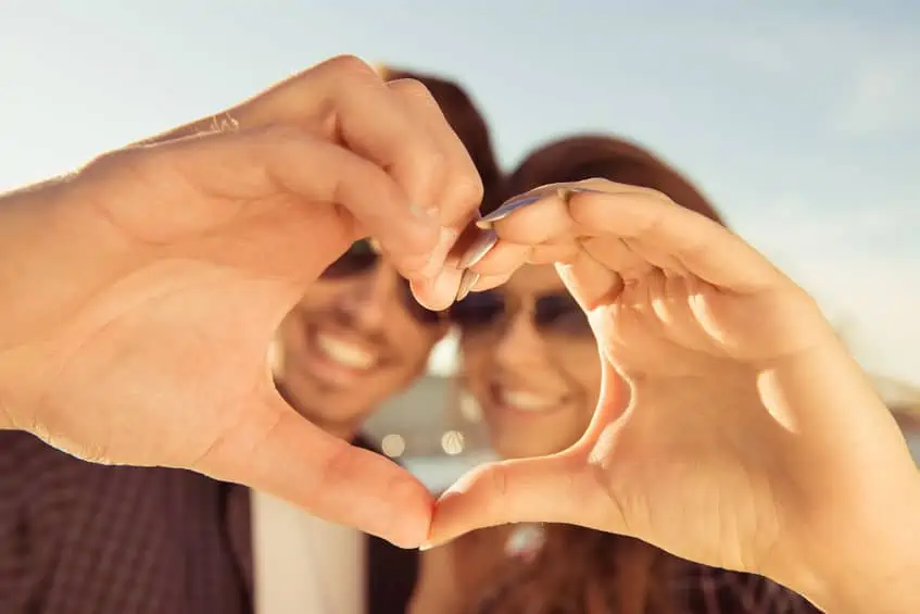 A couple making a cute \"heart\" with their hands together.