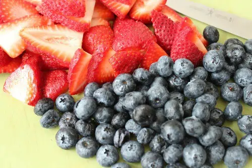 Cut up strawberries and blueberries.