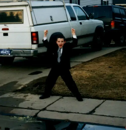 A little boy standing in front of a car