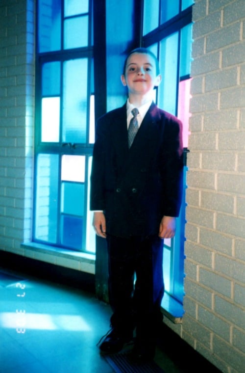 A young man standing in front of a window