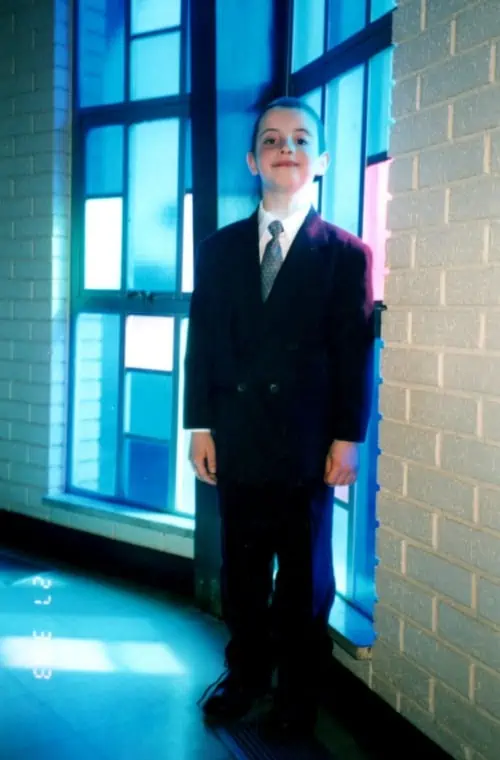 A young man standing in front of a window