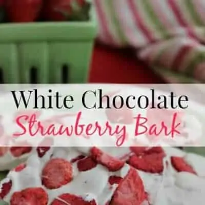 A plate of white chocolate strawberry bark in front of a green basket of fresh strawberries.