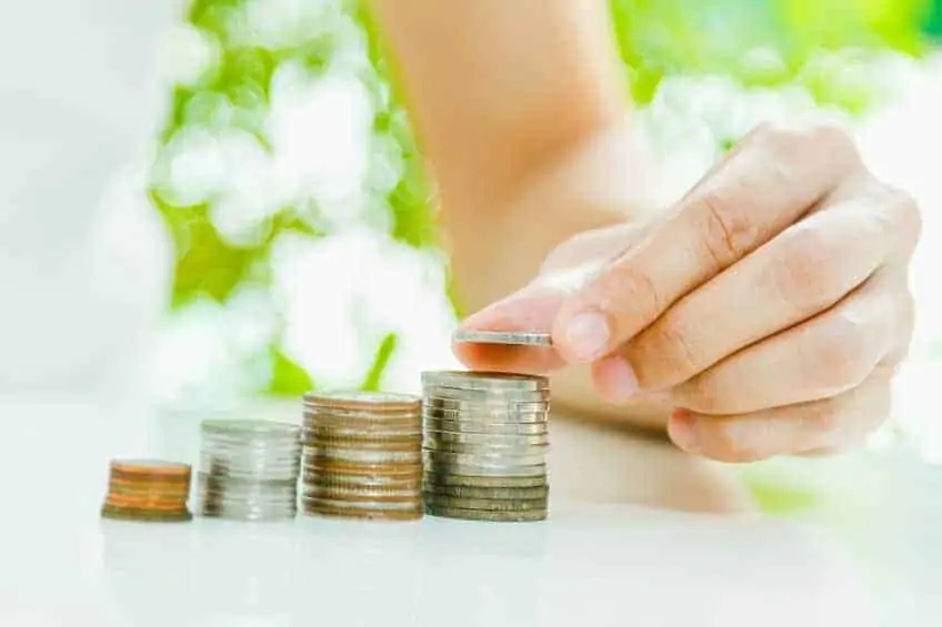 A woman stacking coins on top of each other from pennies, nickles, dimes, and quarters.