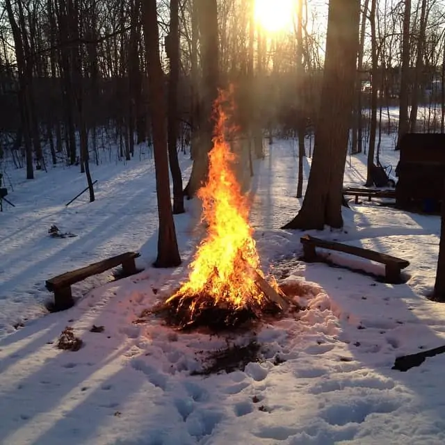 A bonfire in the middle of a field of snow.