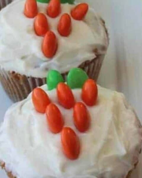 Cupcakes with orange and green candies to look like carrots on top of the cupcakes.