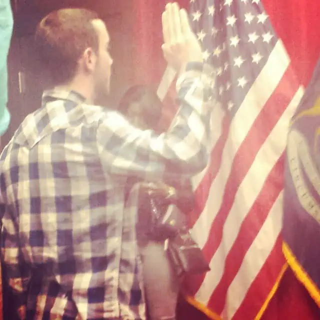 A young man raising his right hand to take an oath for the United States.