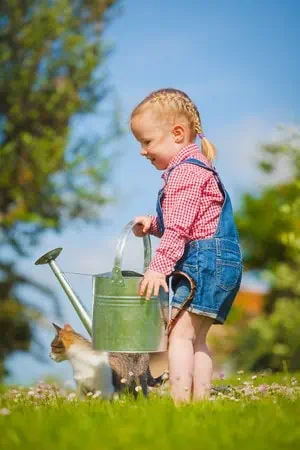 A little girl with a canteen of water to take care of her garden. 