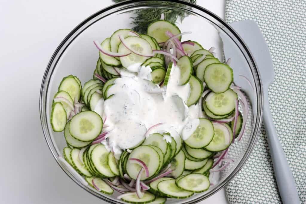 Mix the dressing with the cucumbers and onions.