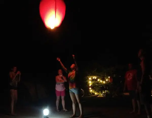 A group of people standing around a lighted lantern.