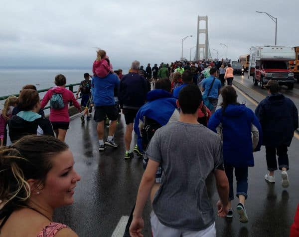 A large crowd of people taking a walk together across the bridge.