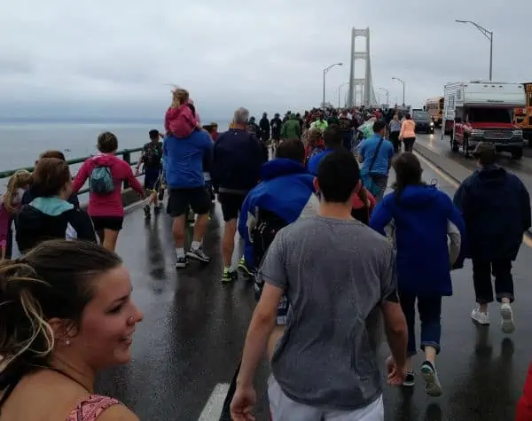 A large crowd of people taking a walk together across the bridge.