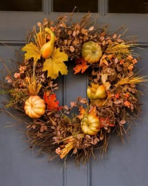 Decorative fall wreath with leaves and pumpkins on the door.