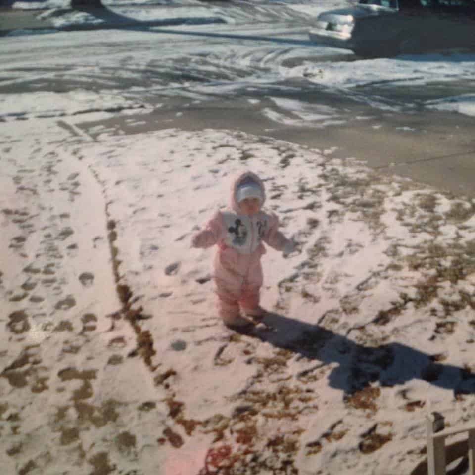 A little boy that is standing in the snow on a beach.