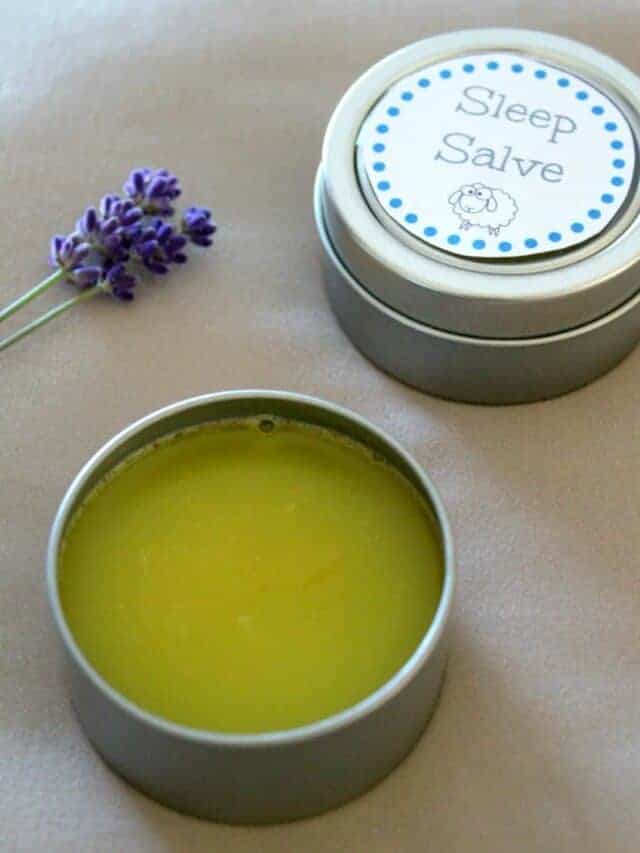 Small containers of homemade sleep salve next to lavender flower.