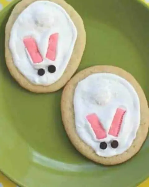 Two Easter bunny sugar cookies on a green plate.