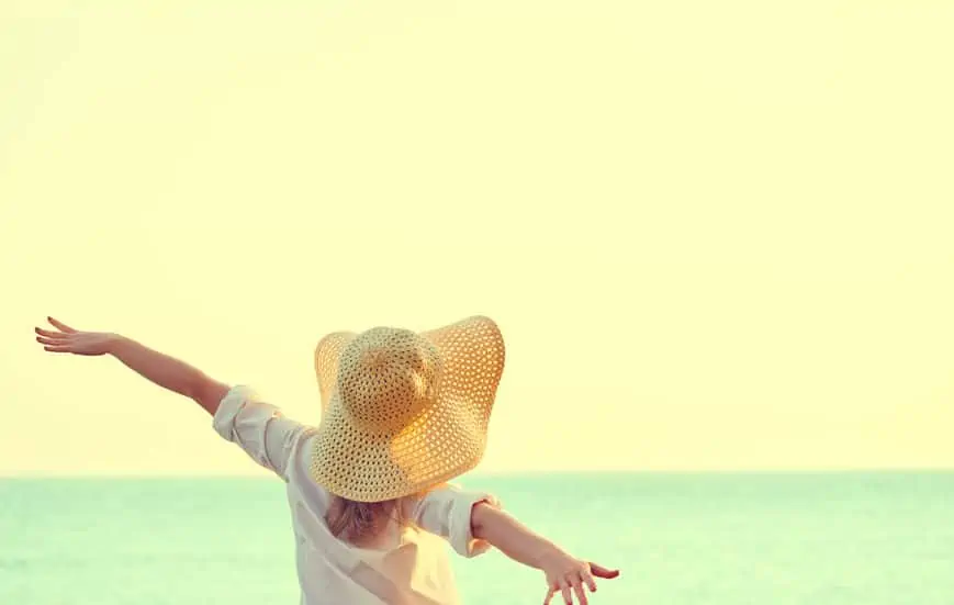 happy beauty woman in hat relaxes and enjoys the sunset over the sea on the beach