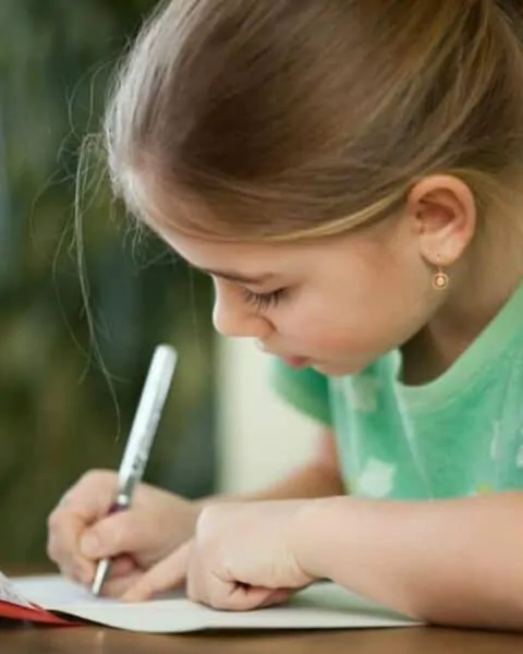 A little girl is writing a letter.
