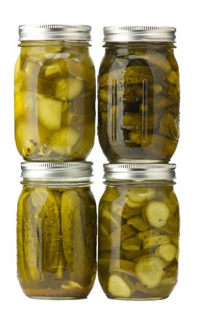 Four jars of assorted homemade pickles isolated