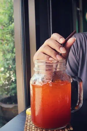 woman drinking ice tea with lemon on a jar
